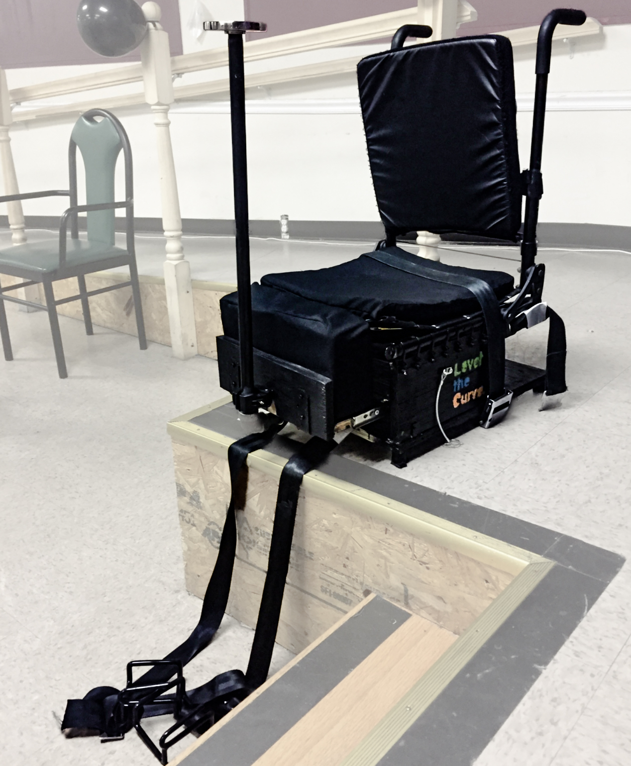 Black padded chair with a pole attached to the front of it